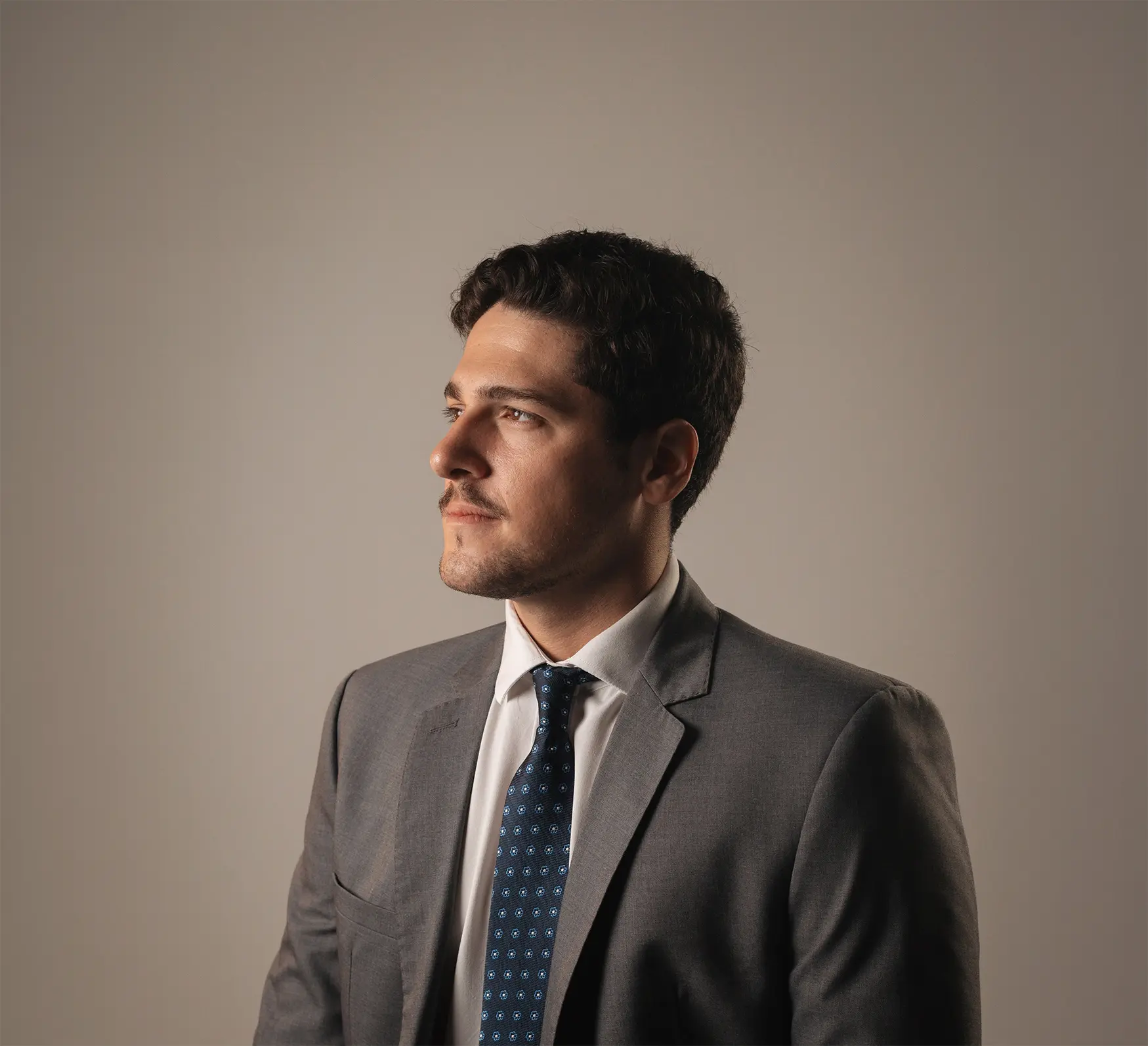 Retrato profissional de Arthur de perfil em terno cinza e gravata.
