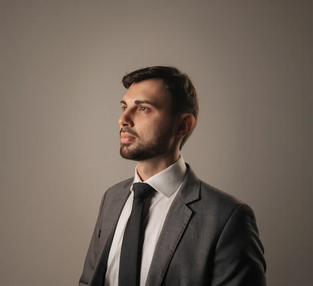 Retrato profissional de Marcelo de perfil em terno cinza e gravata.