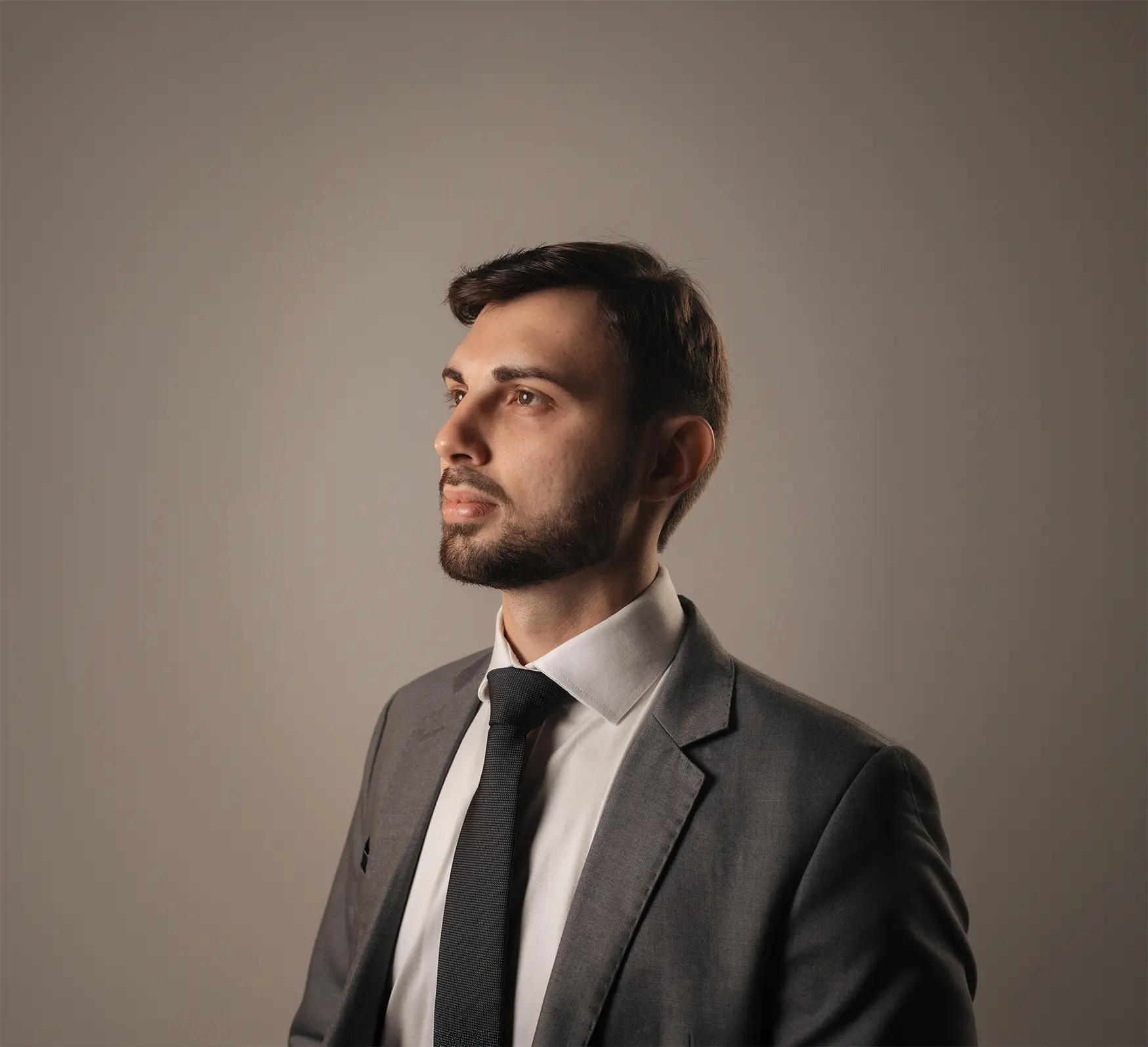 Retrato profissional de Marcelo de perfil em terno cinza e gravata.