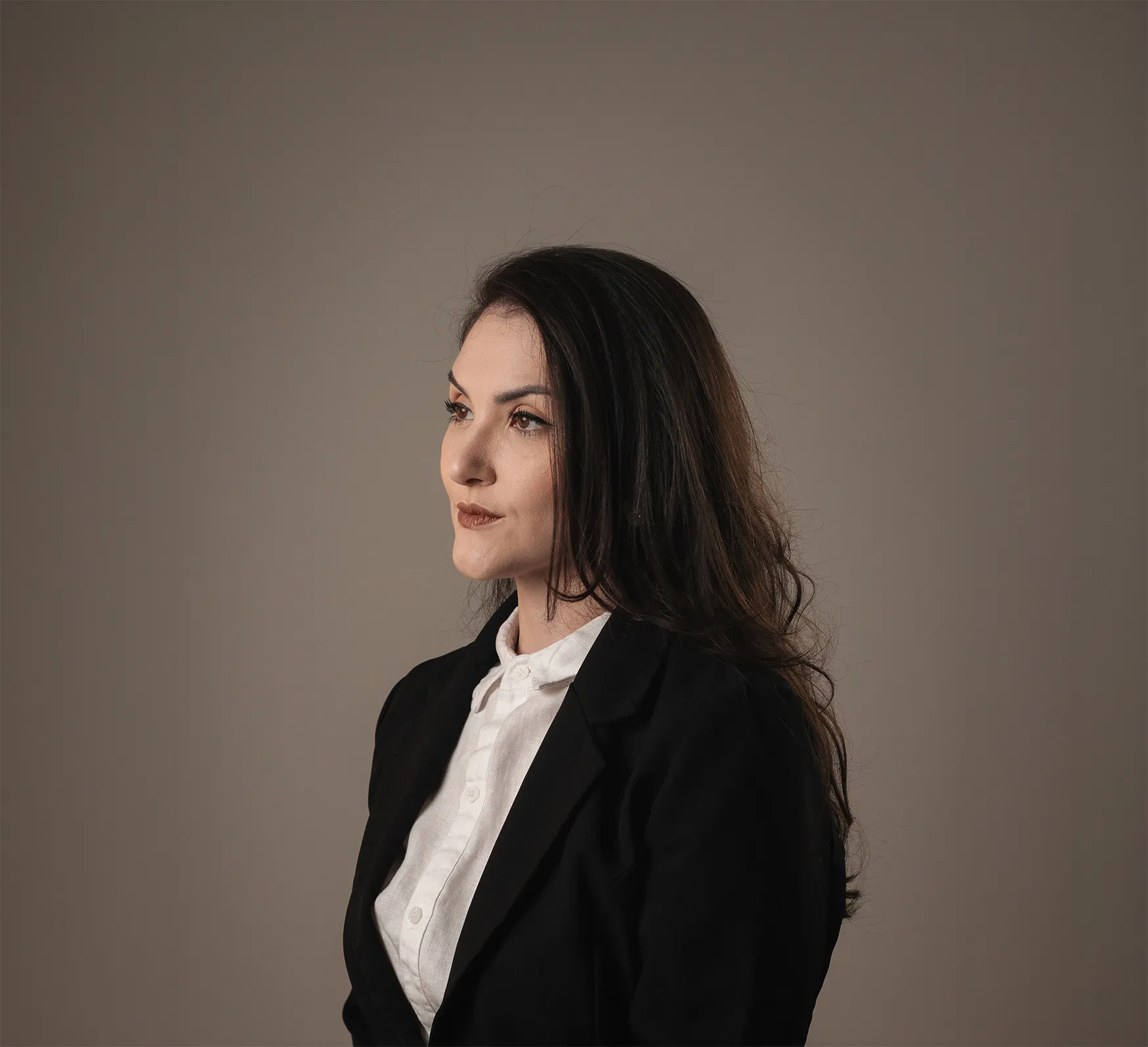 Retrato profissional de Maria de perfil em blazer preto e camisa branca.