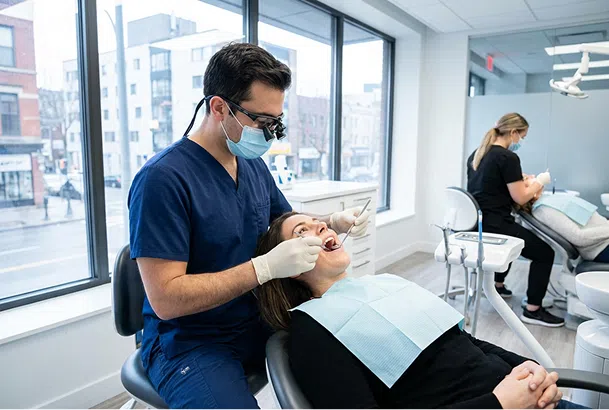 Dentista atende paciente em consultório odontológico moderno.